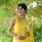 Bright yellow designer saree with floral art displayed by a smiling woman outdoors
