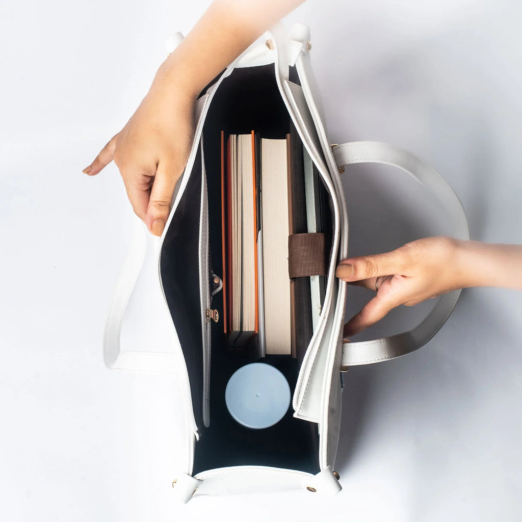 Interior of a large designer tote bag showcasing books and a circular item inside