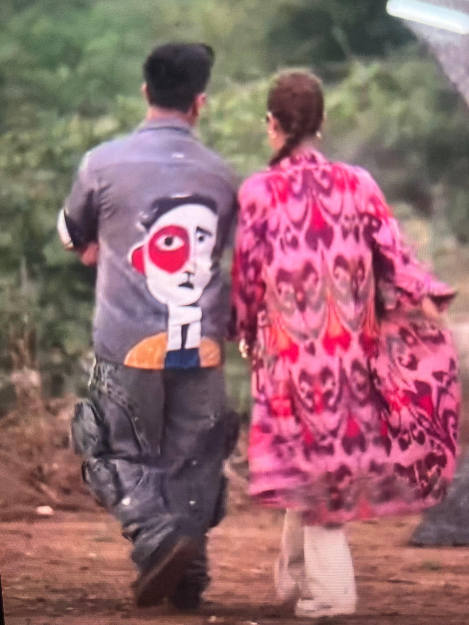 Stylera artistic printed resort shirt on man featuring large abstract face back print as couple walk outdoors
