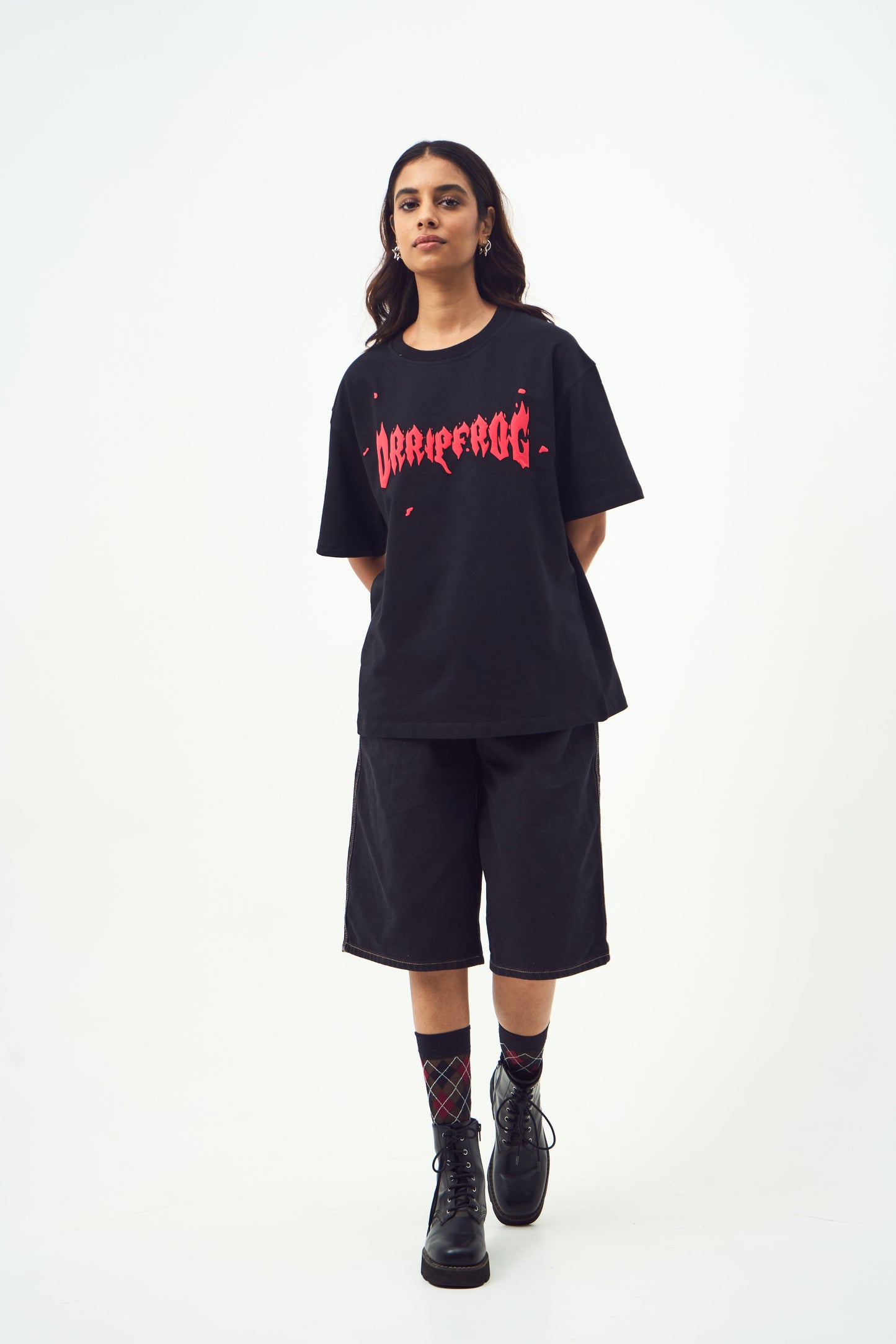 Model wearing Stylera black oversized edgy graphic tee for men and women with long shorts and combat boots