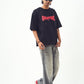 Model in black oversized edgy graphic tee for men and women paired with faded jeans red black sneakers