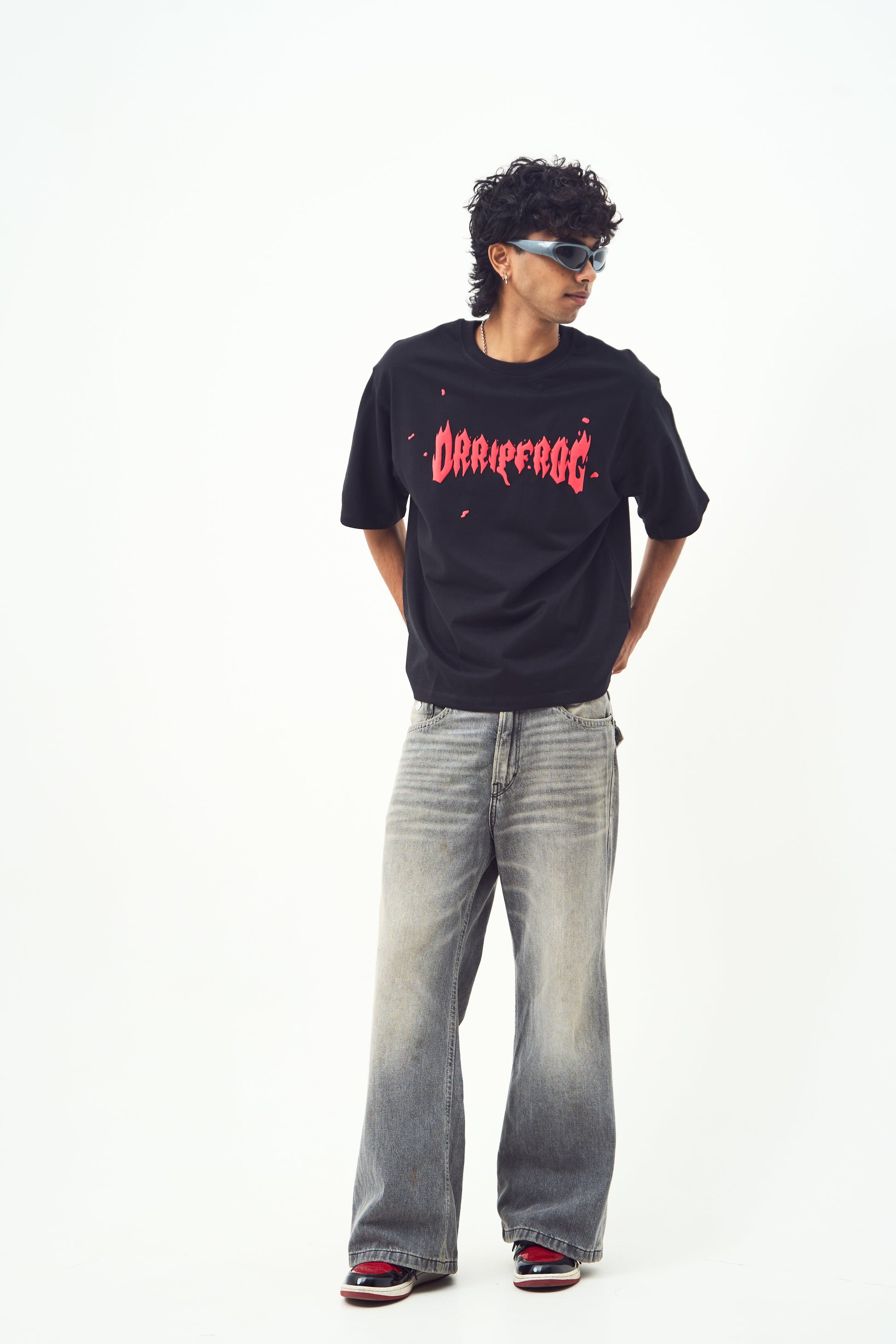 Male model wearing Stylera black edgy graphic tee for men and women with faded wide leg jeans