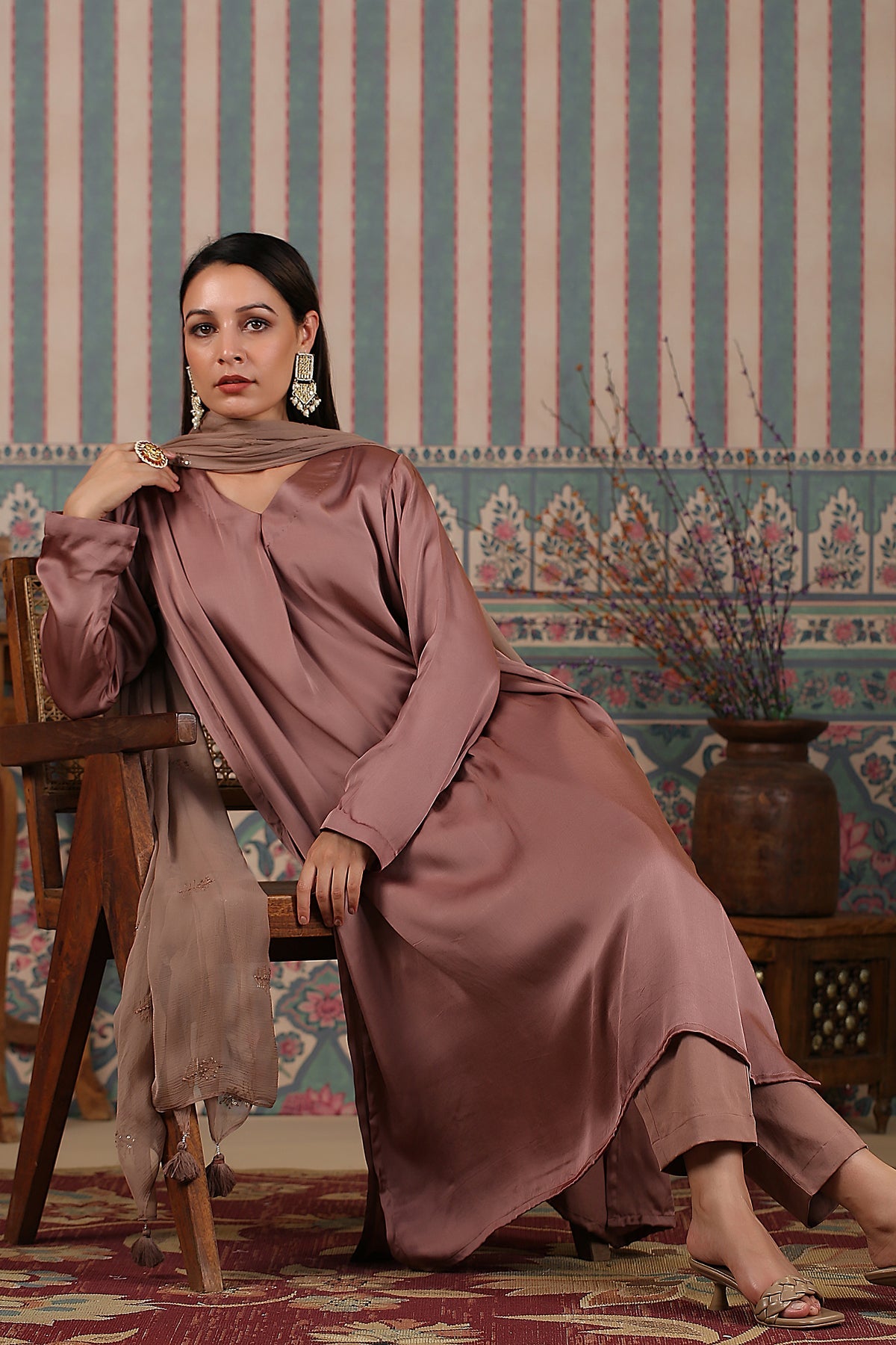 Elegant long kurta with dupatta in soft fabric, styled with traditional earrings and a wooden chair