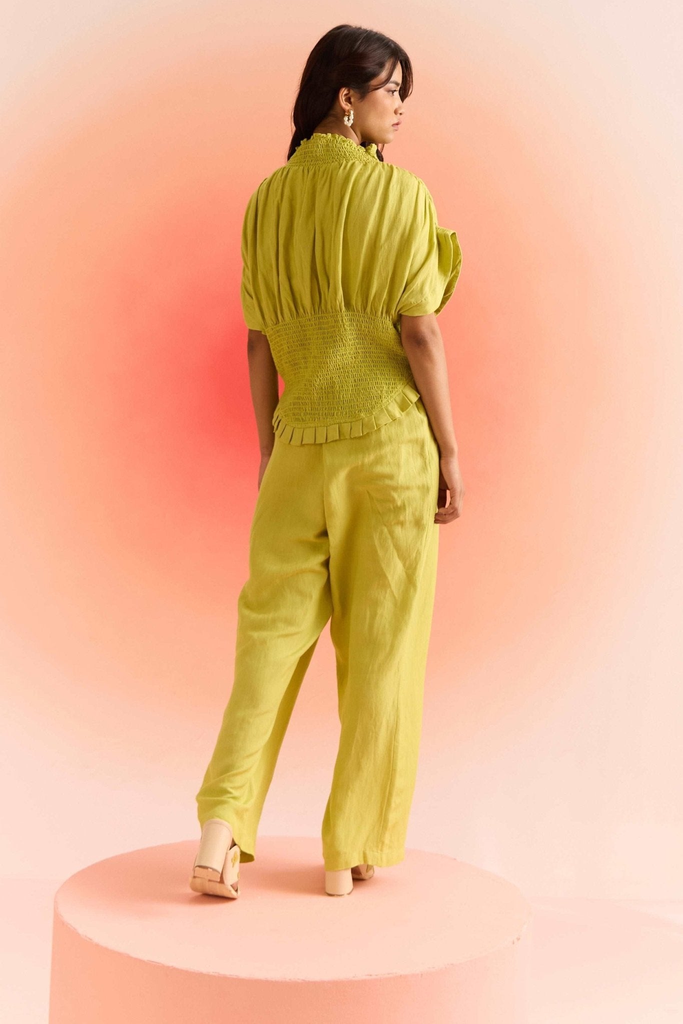 Woman wearing Stylera green smocked top with puff sleeves and matching green pants