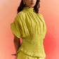 Stylera green smocked top with puff sleeves and ruffled hem on woman