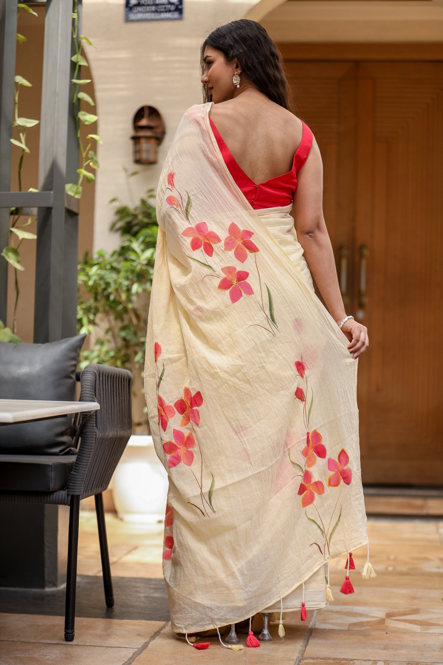 Elegant floral print cream saree with vibrant red flowers and tassels, perfect for festive occasions