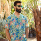 Man wearing a floral short sleeve casual shirt in a tropical garden setting