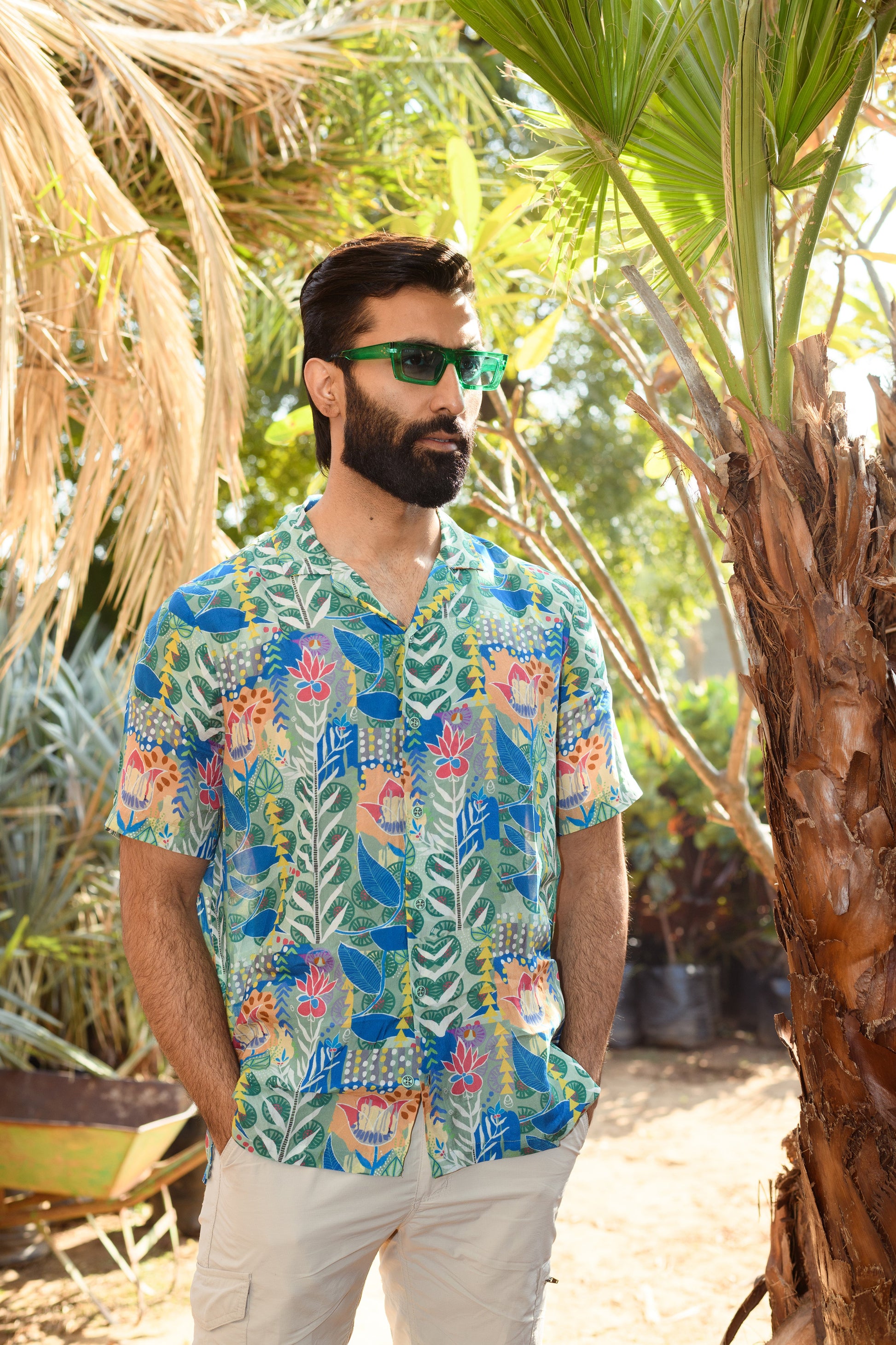 Man wearing a floral short sleeve casual shirt in a tropical garden setting