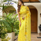 Stylish woman wearing a floral viscose chiffon saree with mukaish work in yellow, standing outdoors