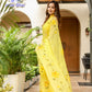 Bright yellow floral viscose chiffon saree with mukaish work, elegantly worn outdoors