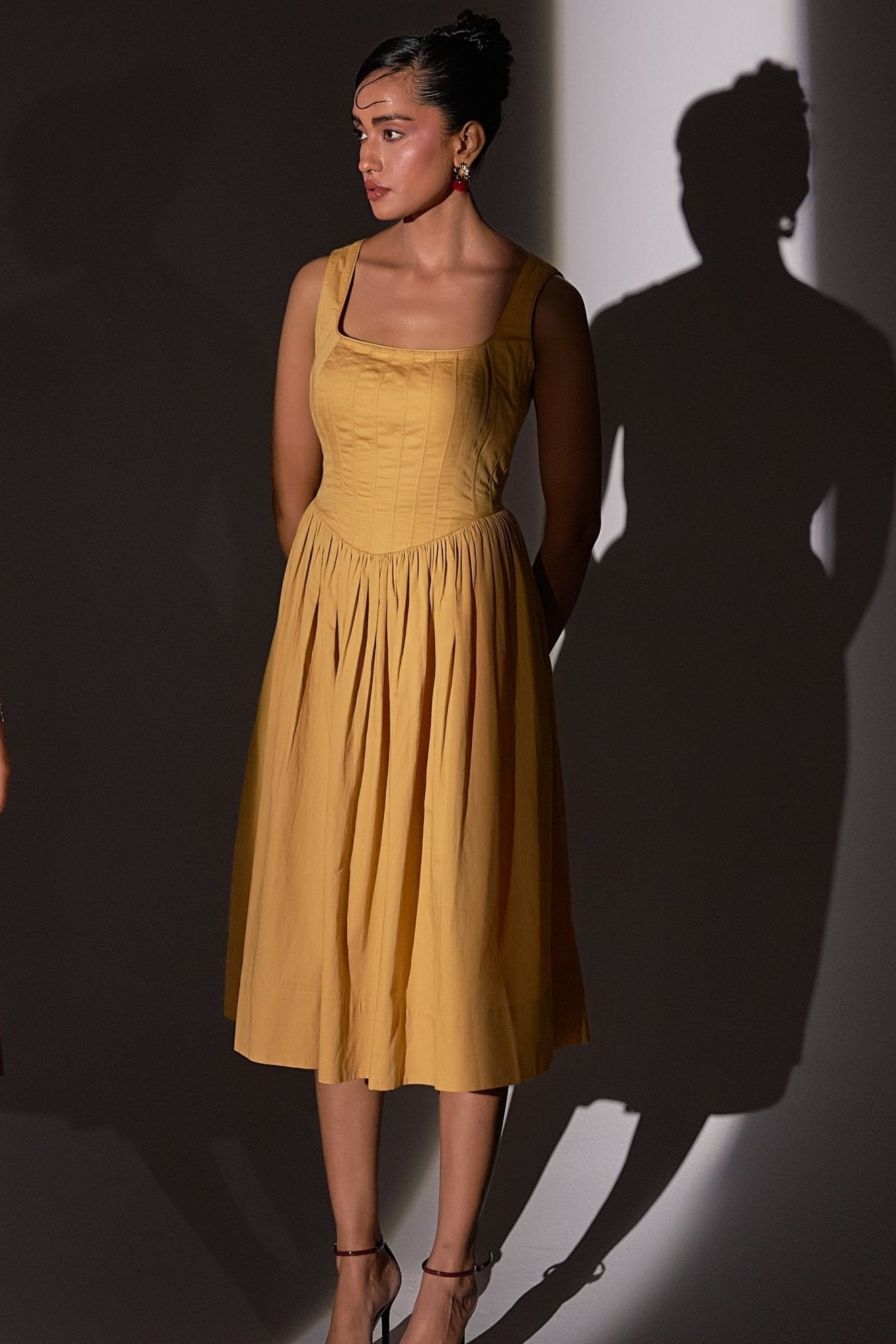 Stylera gold cotton corset dress with sleeveless design and midi length worn by model