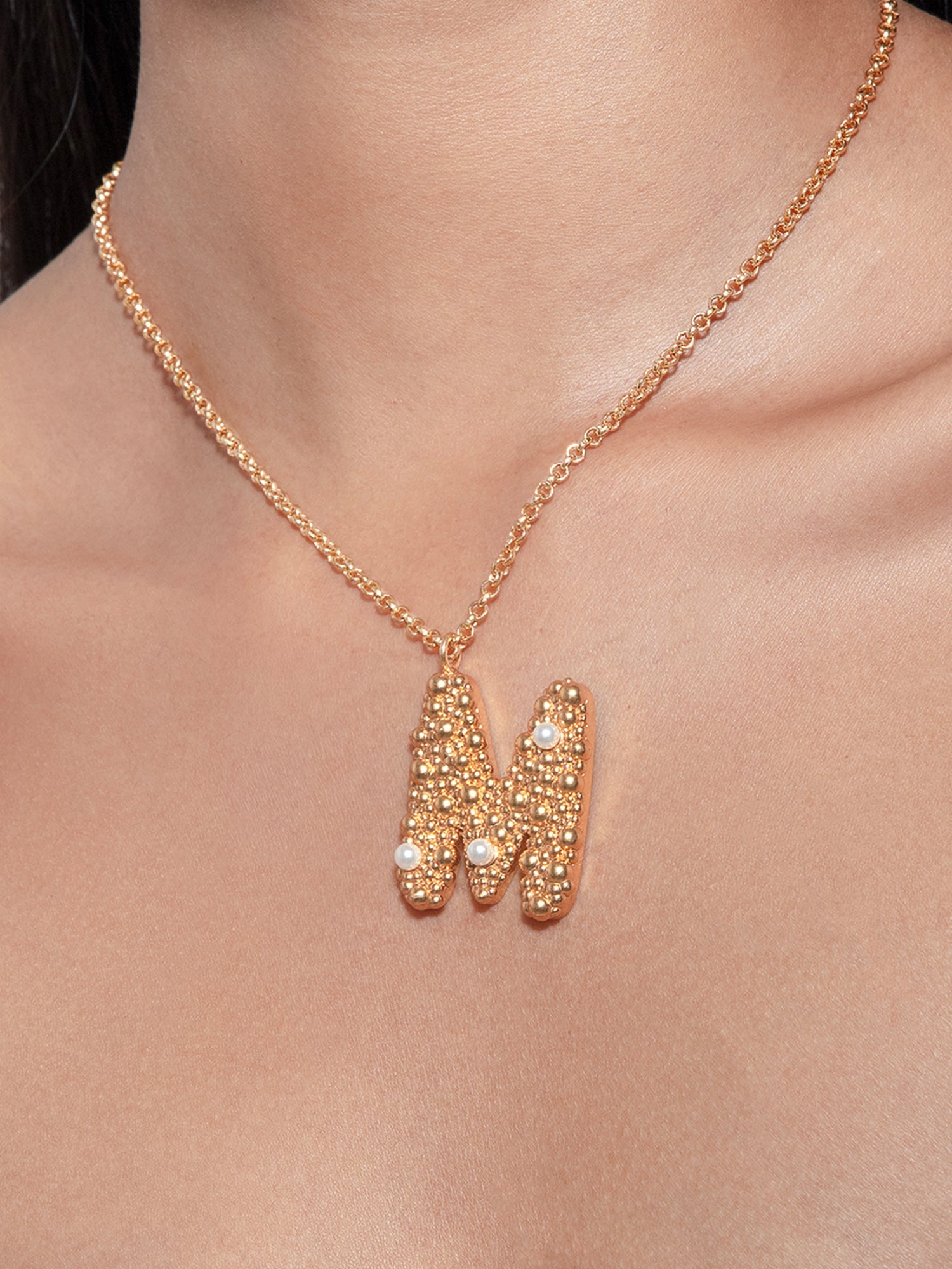 Stylera gold letter M necklace pendant with textured gold and small pearl accents on delicate chain