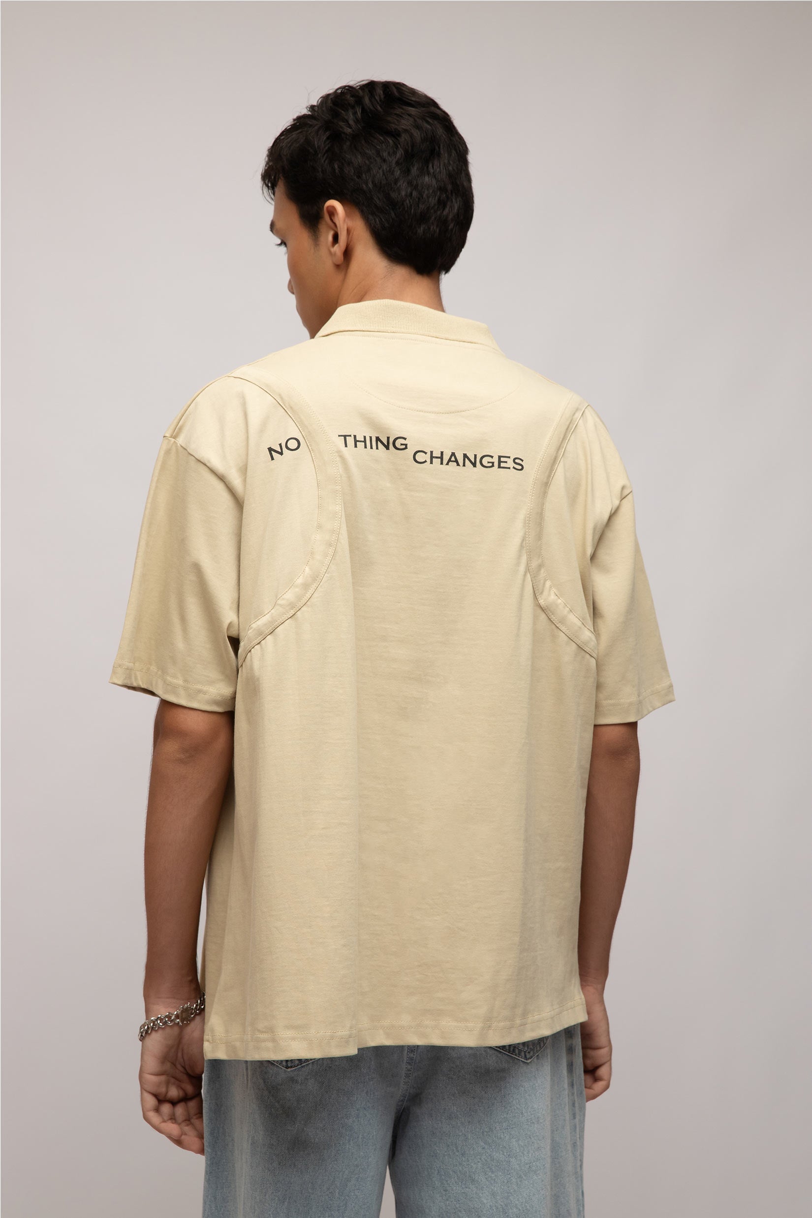 Stylera beige short sleeve graphic polo shirt for men back view with printed NO THING CHANGES text and relaxed fit