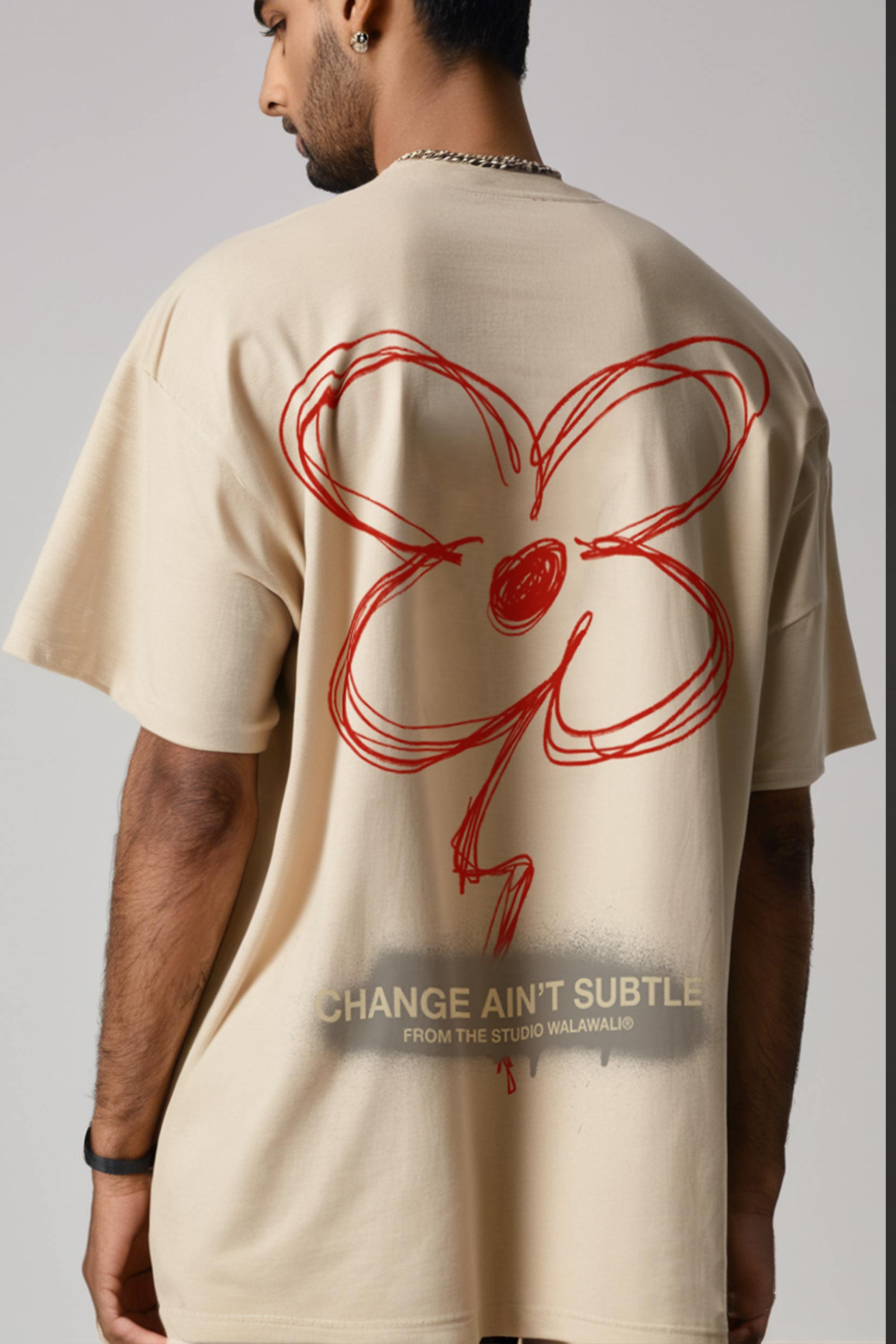 Back view of model wearing Stylera beige tee with red scribble flower and slogan graphic print oversized tee