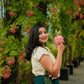 Woman wearing a green embroidered linen top by Stylera standing outdoors near flowering trees