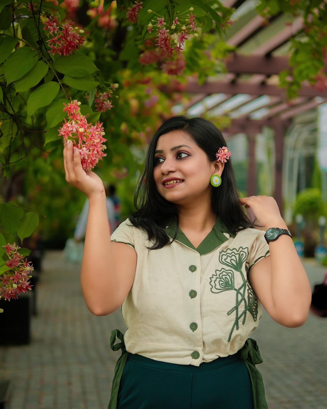 Stylera green embroidered linen top with floral design worn by woman in outdoor garden setting