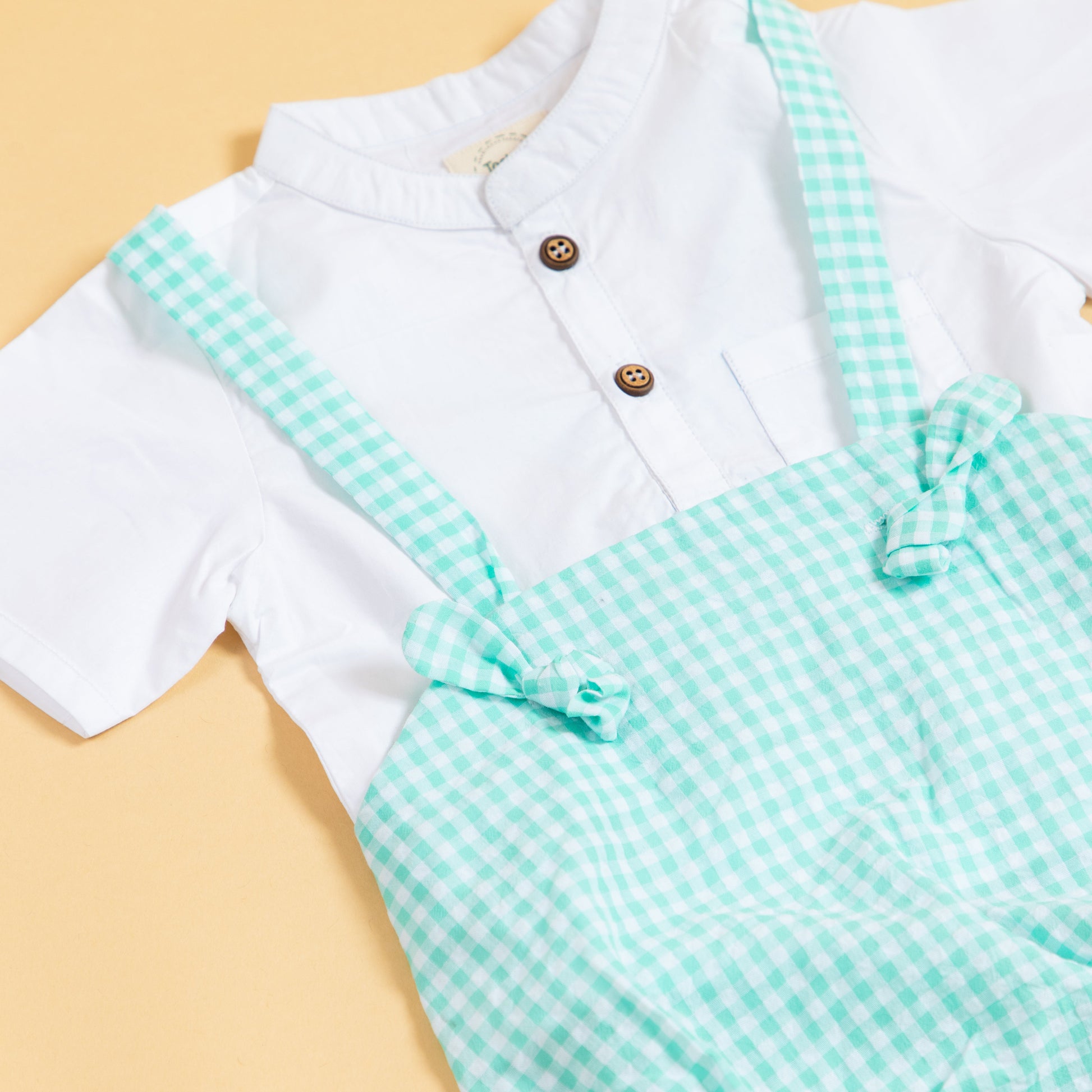 Cute green gingham baby romper with button details and adjustable straps for stylish infants