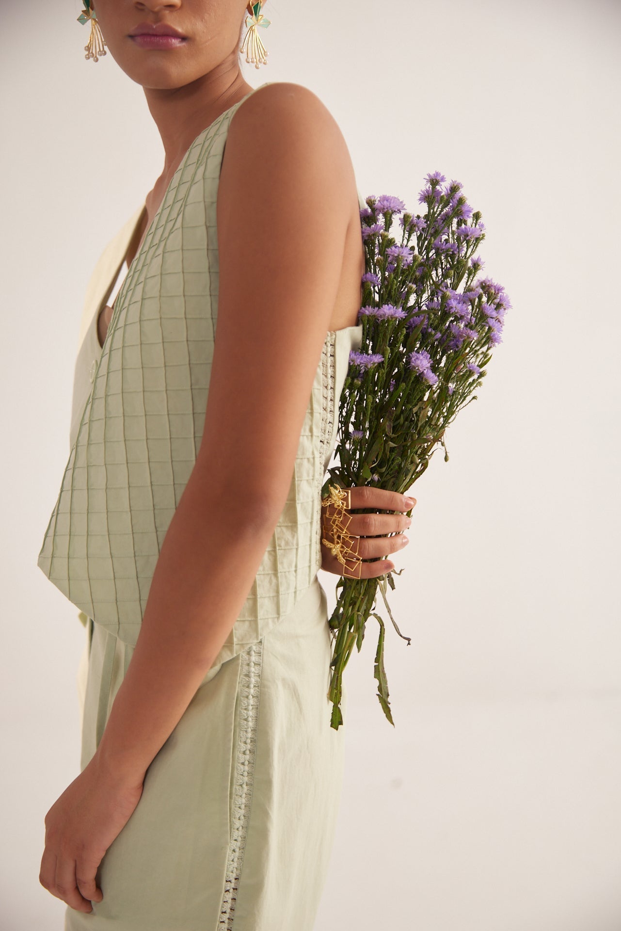 Stylera green lace straight fit trousers worn by model holding purple flowers