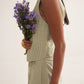 Stylera green lace straight fit trousers worn with a matching sleeveless top holding purple flowers