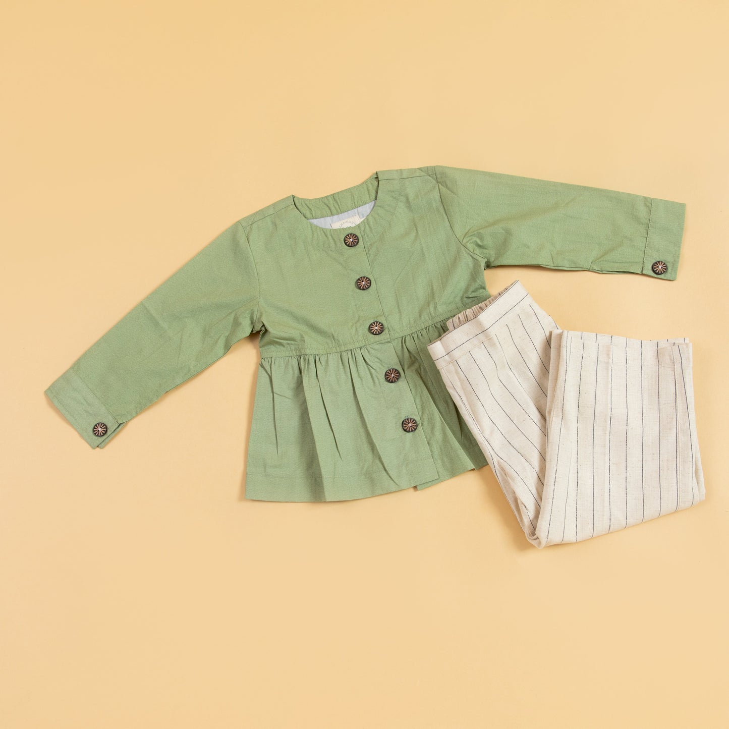 Green peplum outfit for women featuring a button-up top and striped trousers
