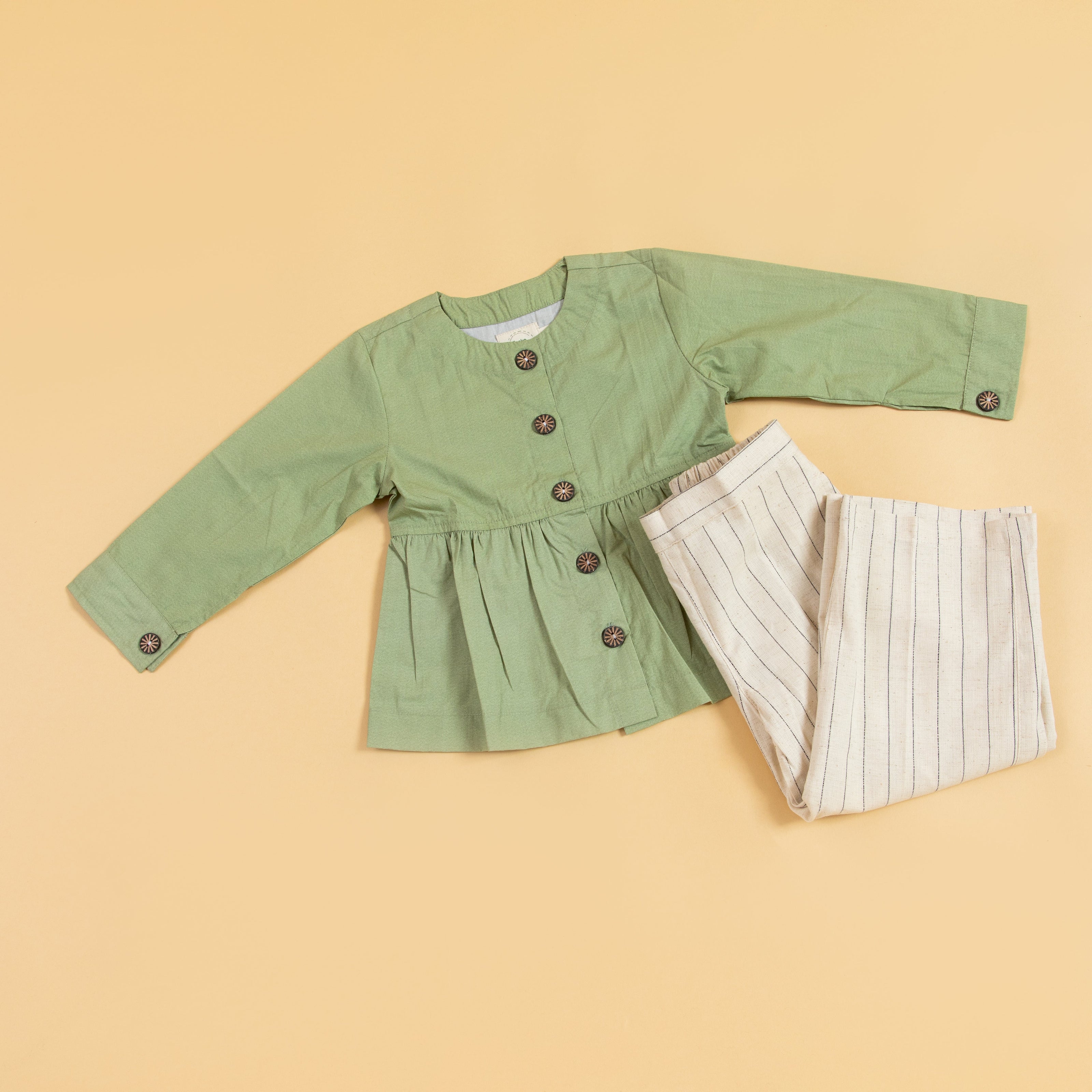 Green peplum outfit for women featuring a button-up top and striped trousers