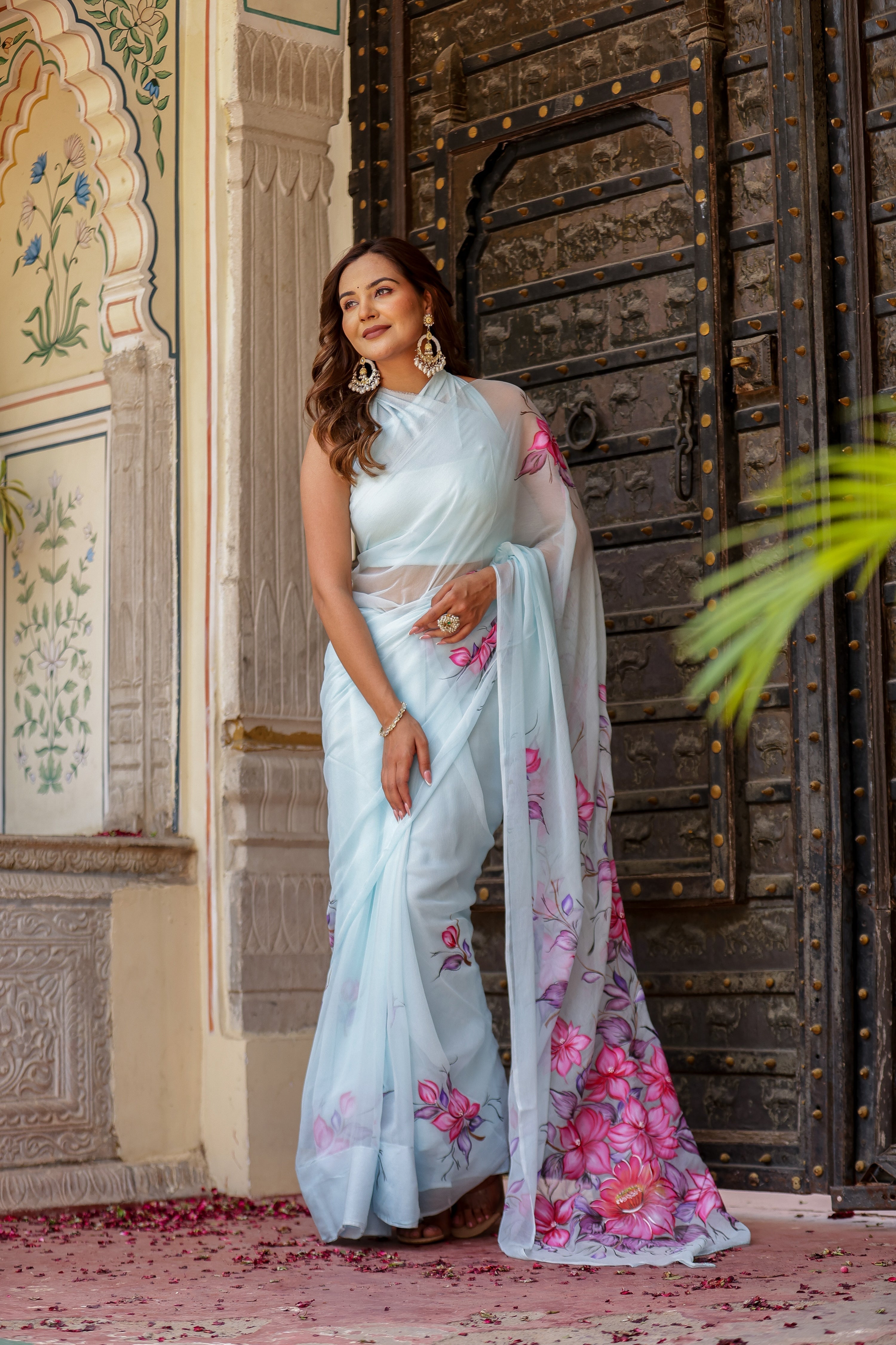 Elegant woman wearing a handcrafted saree with floral print, featuring a light blue color and vibrant flowers