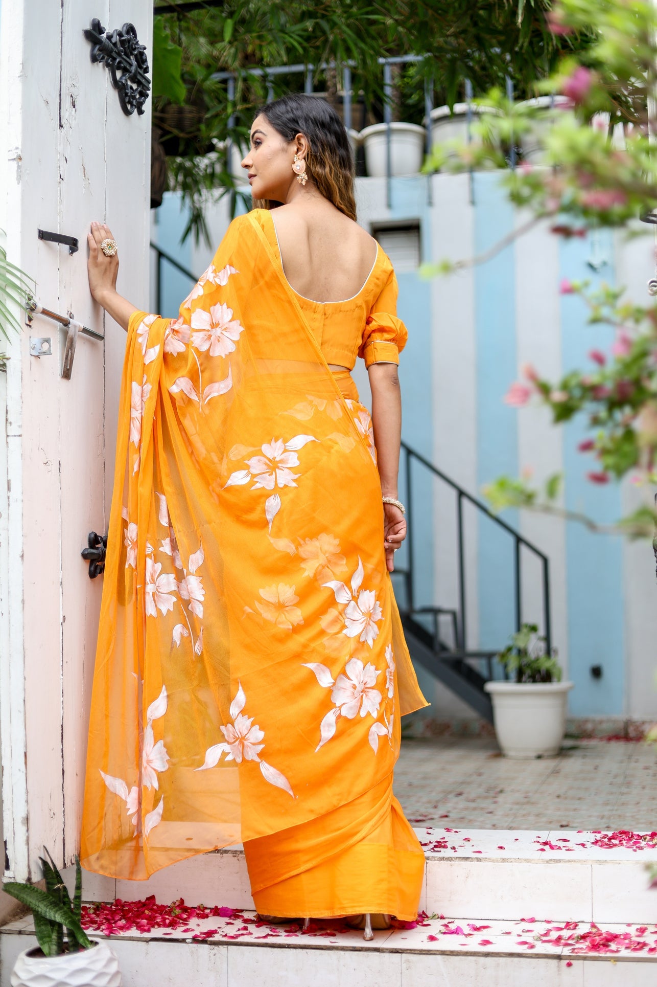 Elegant handpainted chiffon saree in bright orange with floral designs for festive occasions