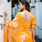 Elegant woman wearing a handpainted chiffon saree in bright orange with floral patterns