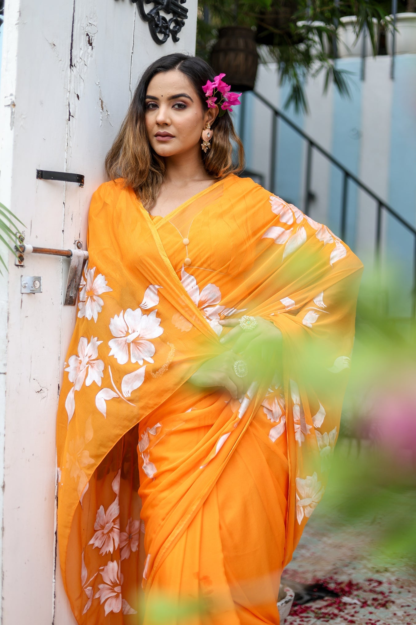 Vibrant handpainted chiffon saree in orange with floral designs, perfect for festive occasions