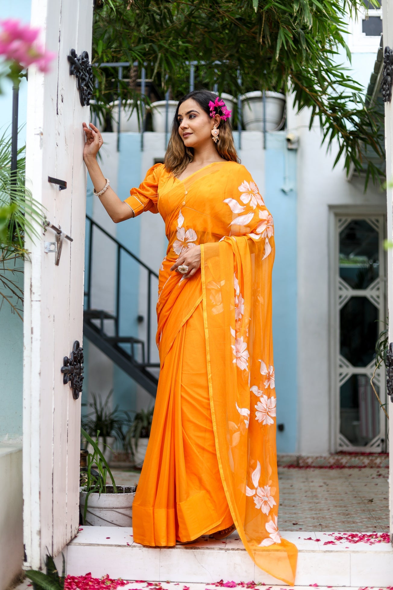 Elegant handpainted chiffon saree in vibrant orange with floral designs, perfect for festive occasions