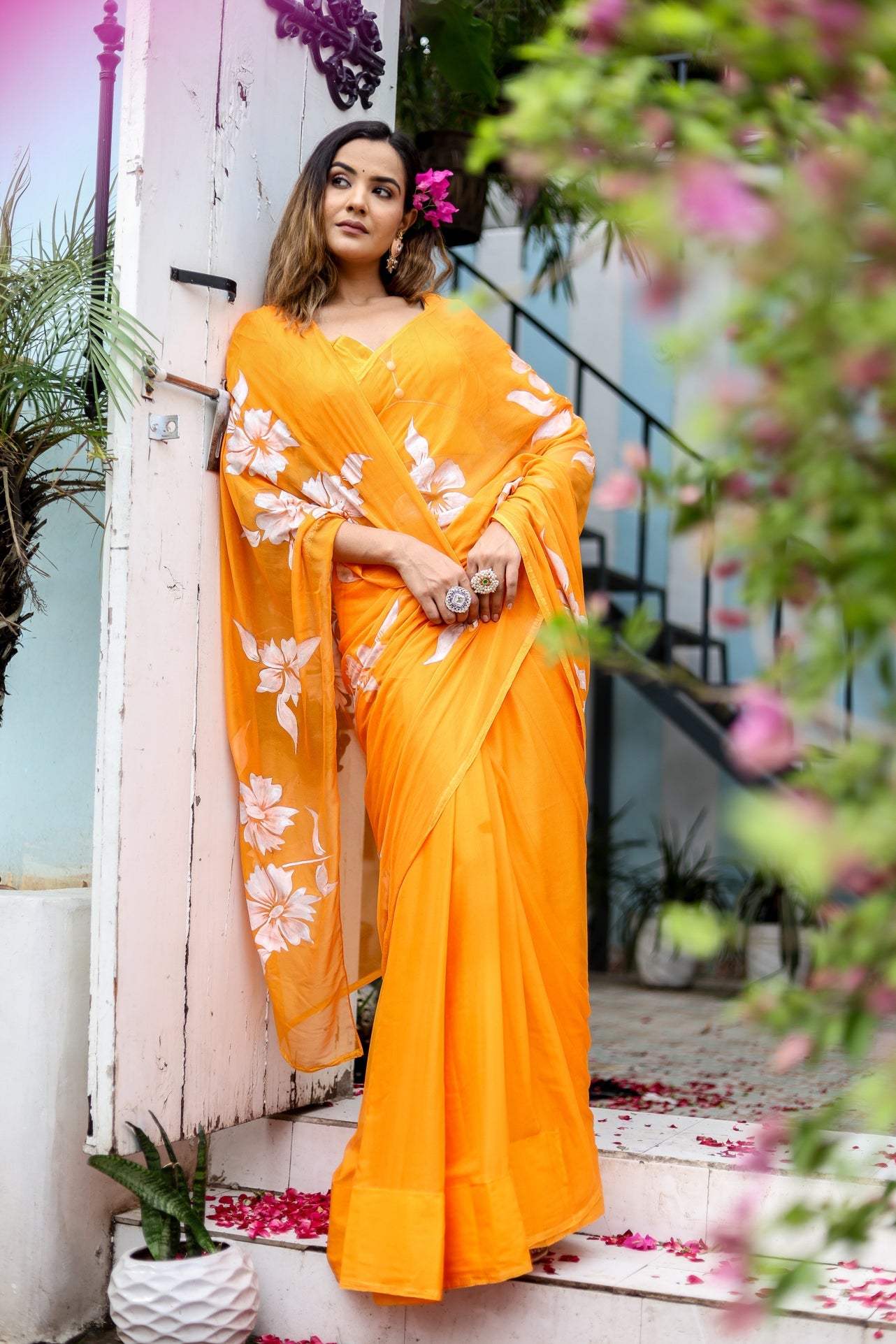 Stunning handpainted chiffon saree in vibrant orange with floral designs, perfect for festive occasions