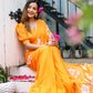 Elegant model wearing a handpainted chiffon saree in orange with floral details, posing gracefully outdoors