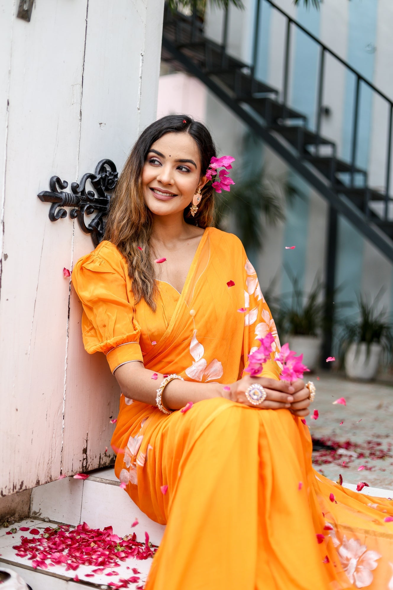 Elegant model wearing a handpainted chiffon saree in vibrant orange with floral designs