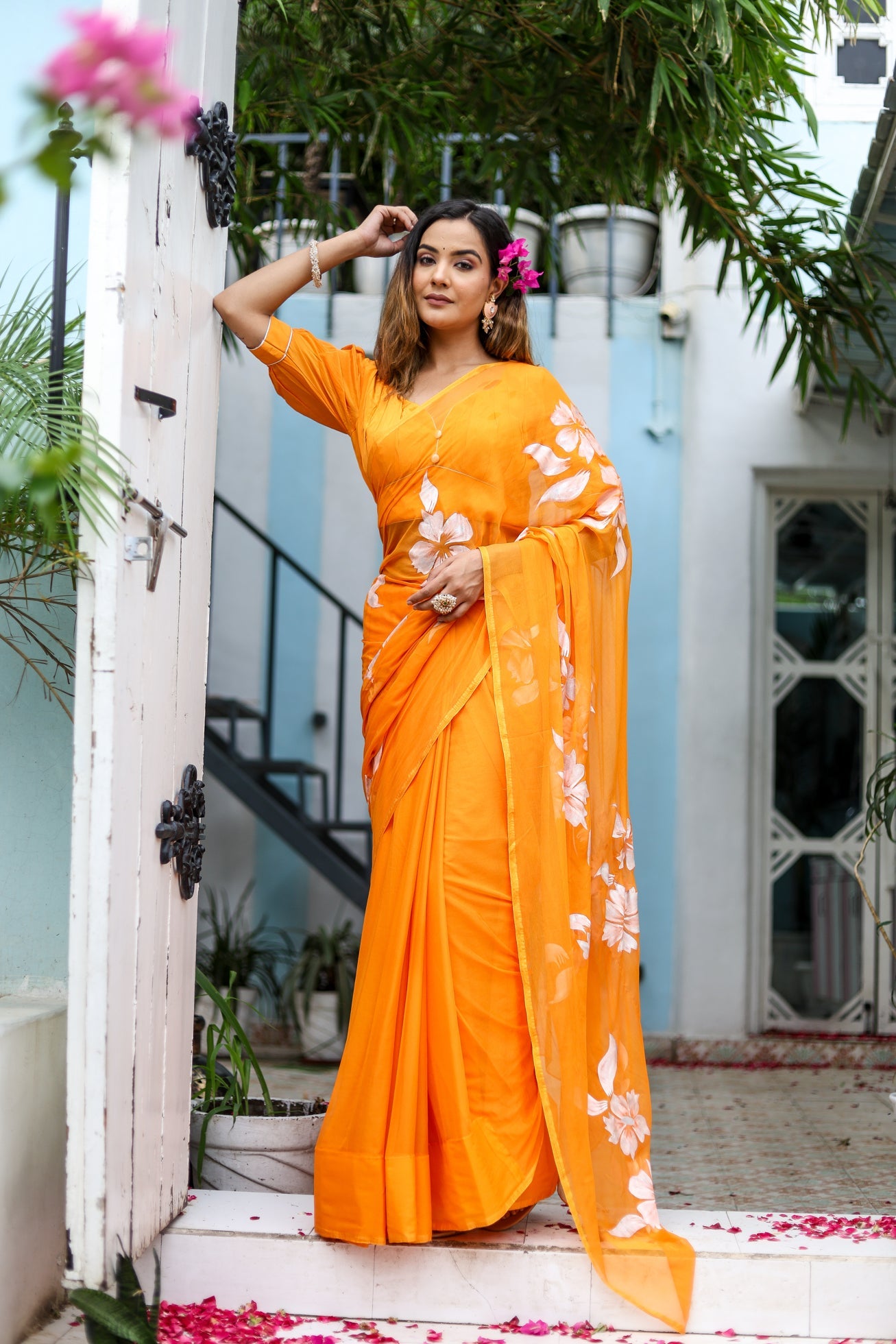 Elegant handpainted chiffon saree in vibrant orange with floral designs for festive occasions
