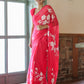 Woman wearing a handpainted chiffon saree rani pink with floral designs, styled elegantly indoors