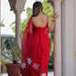 Elegant handpainted red organza saree with floral designs, showcased outdoors for a feminine look