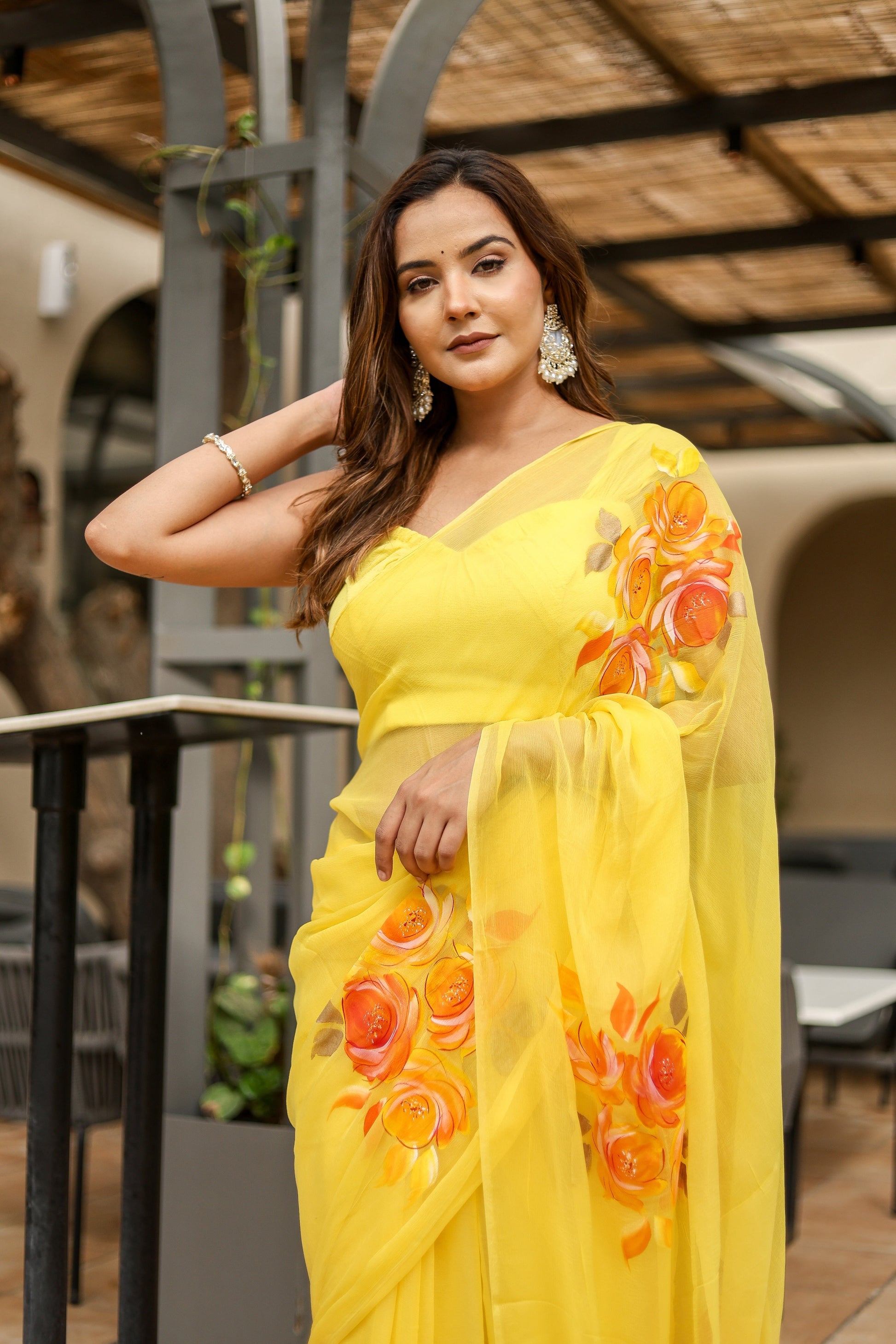 Elegant model wearing a handpainted yellow chiffon saree with floral designs for festive occasions