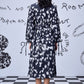Back view of Stylera heart print black dress midi length with long sleeves and cinched waist