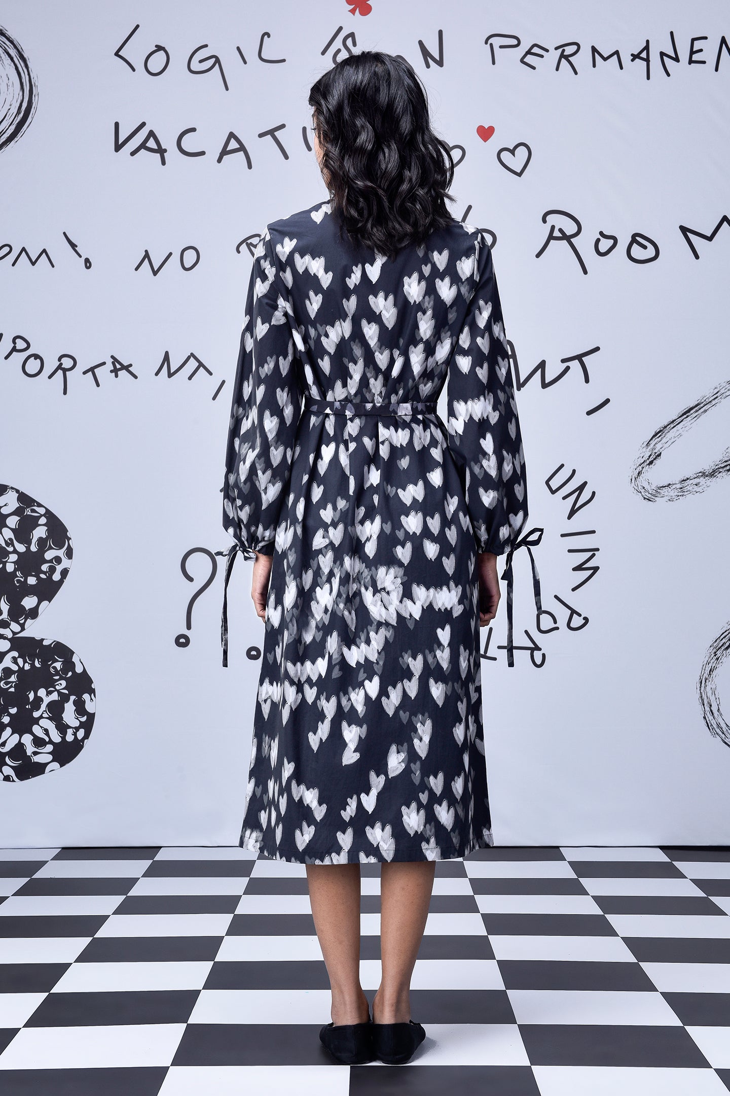 Back view of Stylera heart print black dress midi length with long sleeves and cinched waist