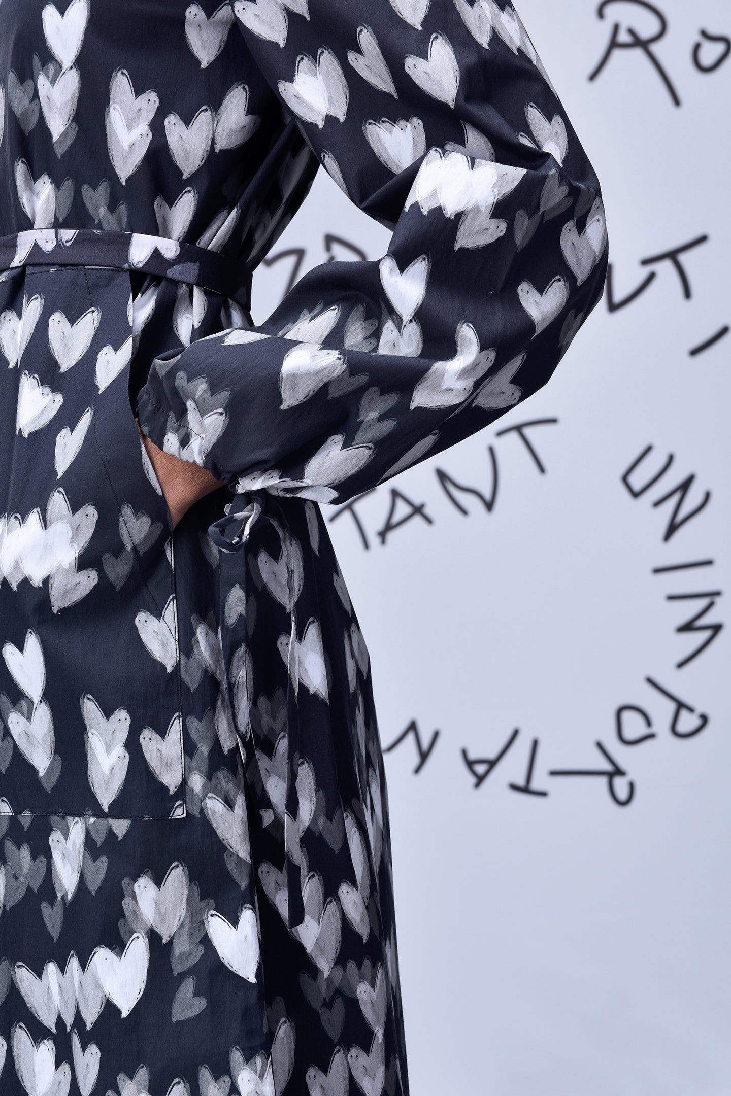 Close up of Stylera heart print black dress with waist tie long sleeve and pocket
