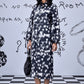 Stylera model in knee length heart print black dress with long sleeves and black flats