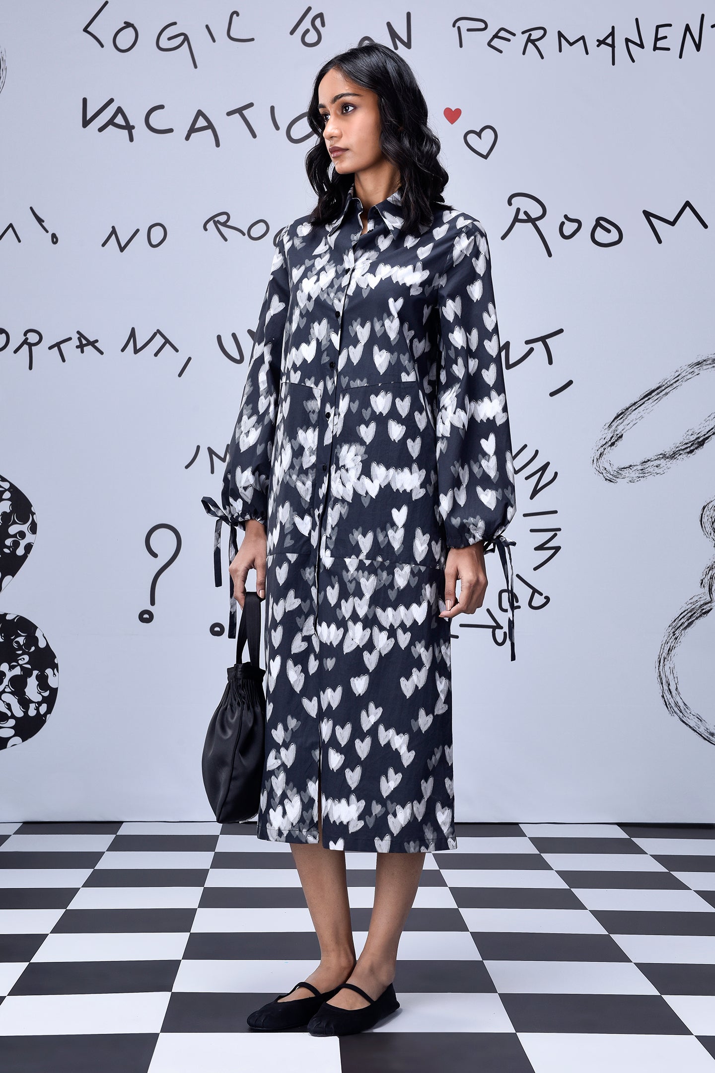 Stylera model in knee length heart print black dress with long sleeves and black flats