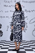 Stylera model in knee length heart print black dress with long sleeves and black flats