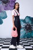 Stylera model wearing black dungaree styled high waist lace up overalls with pink floral handbag and white sneakers