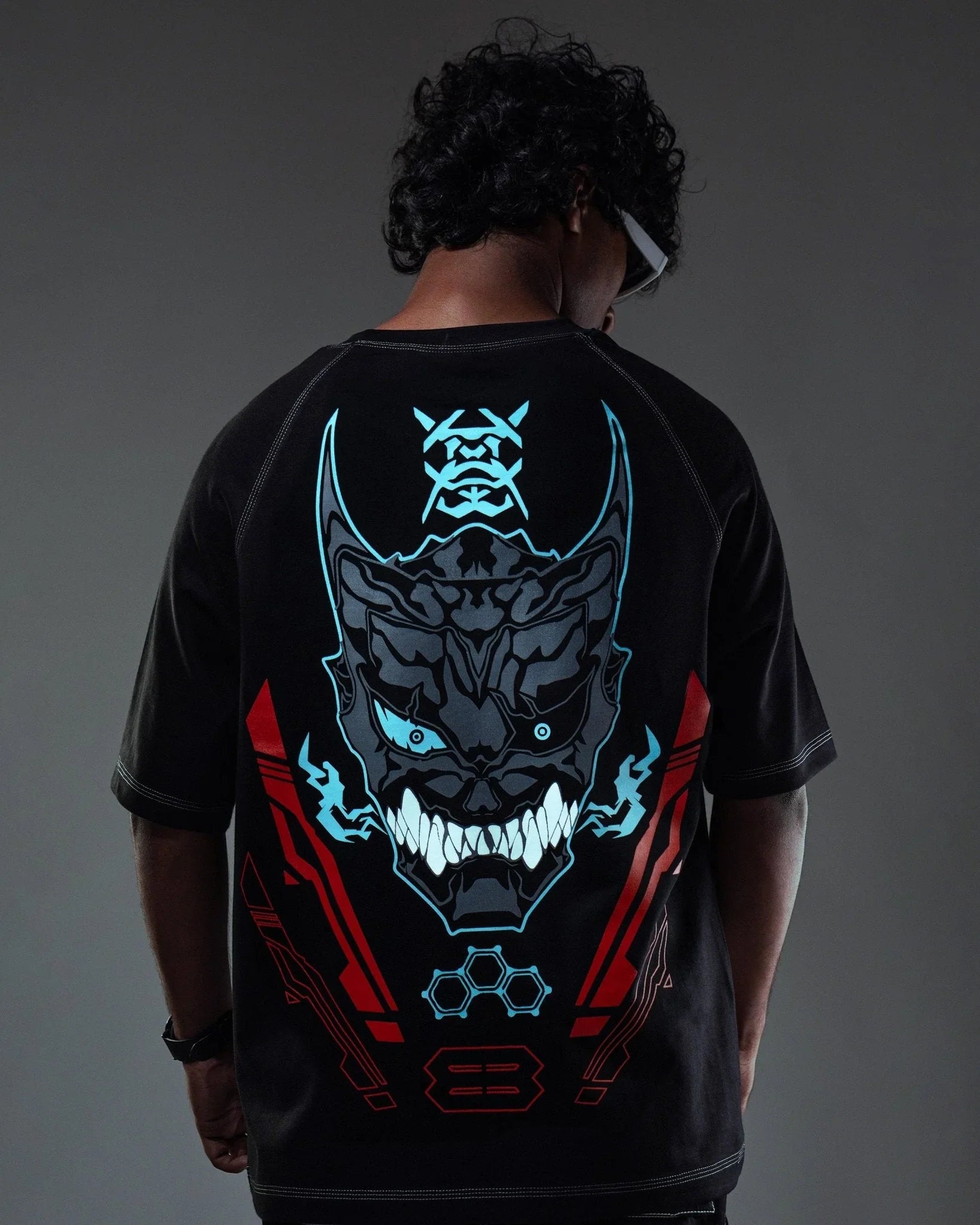 Person wearing a black t-shirt with a detailed graphic design on the back against a dark background