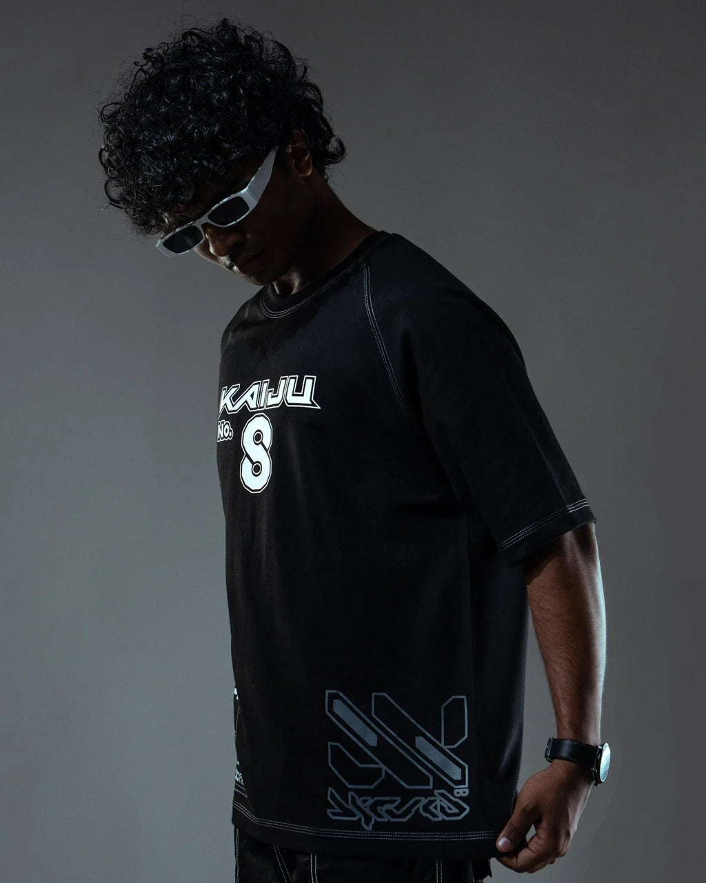 Person wearing a black t-shirt with logos on a dark background