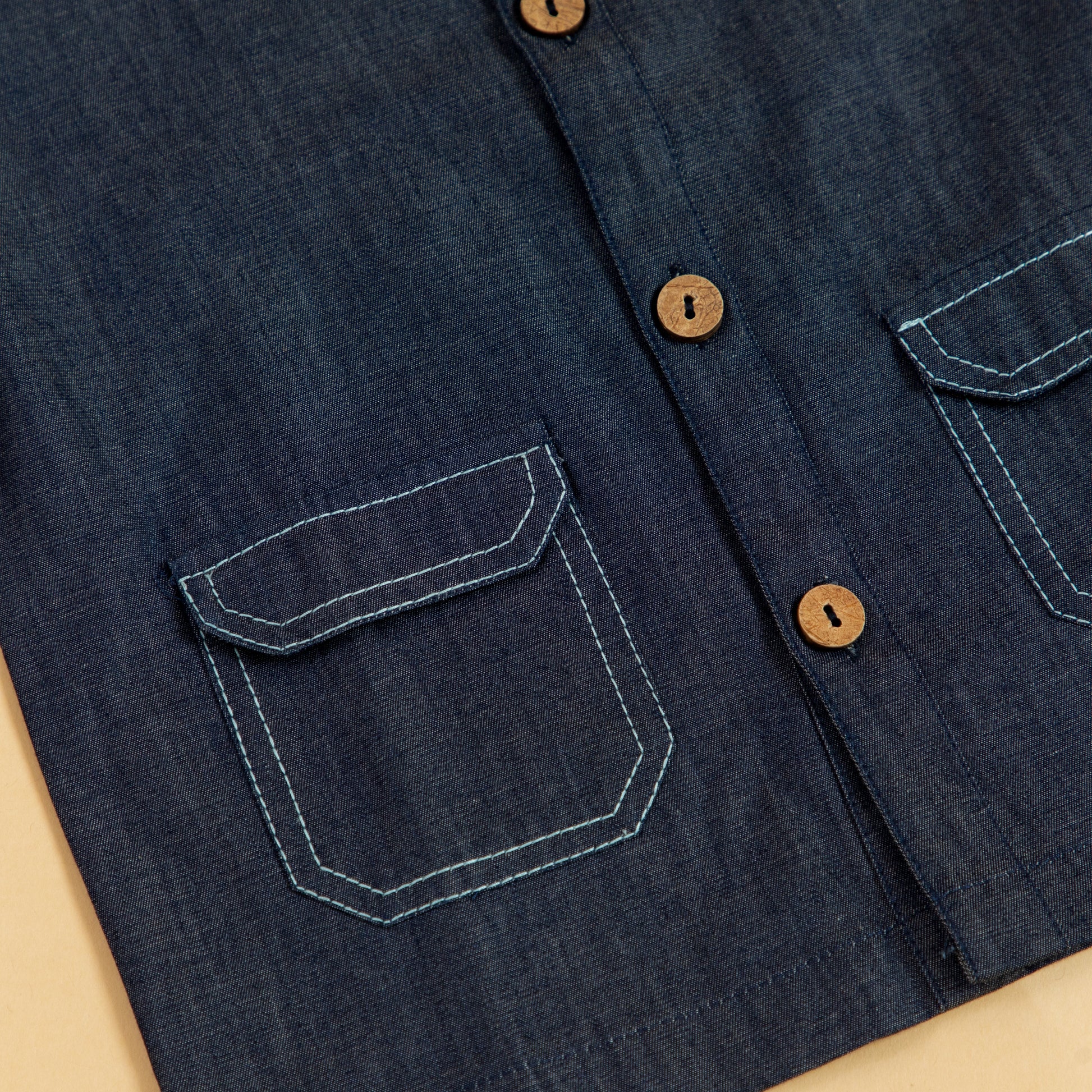 Close-up of kids blue denim jacket featuring button closure and dual front pockets