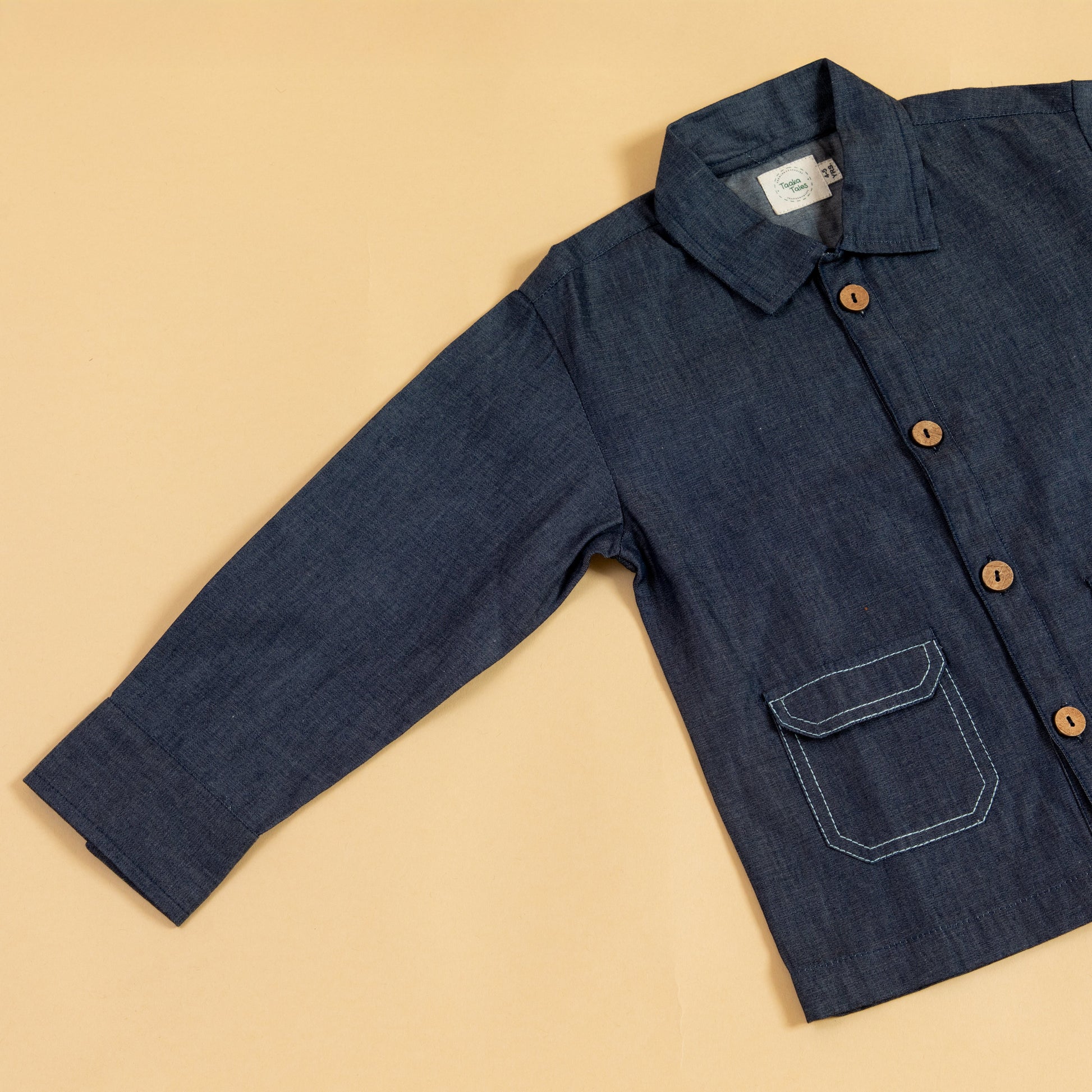 Kids blue denim jacket featuring wooden buttons and a front pocket for a stylish look