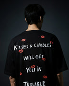 Person wearing a black t-shirt with text and red lip prints on a dark background