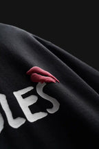 Black sweatshirt with red lips and white text on a dark background